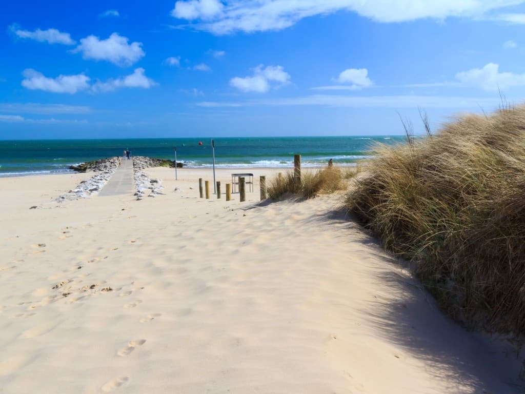 Sandbanks beach with dunes, marram grass and a stone groyne leading into turquoise sea