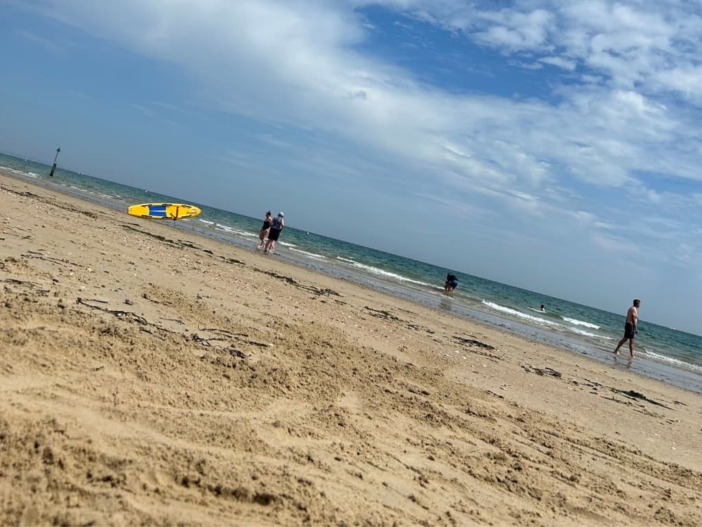 Sandbanks beach with paddleboard, shoreline and shallow blue water on a bright day