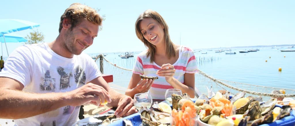 Couple enjoying seafood and wine at a harbour-side restaurant overlooking the water