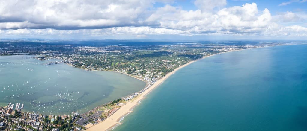 Aerial view of Sandbanks Beach stretching along Poole Bay with clear shallow water